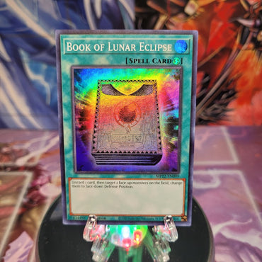 A Super Rare "Book of Lunar Eclipse" card from the Yugioh 2022 Tin of the Pharaoh's Gods Set.