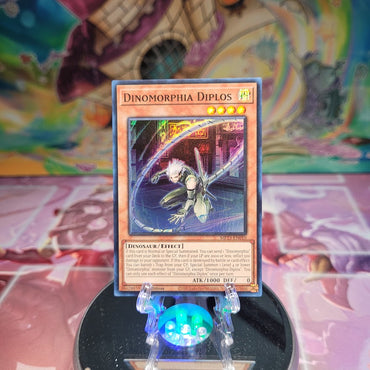 A Super Rare "Dinomorphia Diplos" card from the Yugioh Dueling Heroes Mega-Tin Mega Pack.