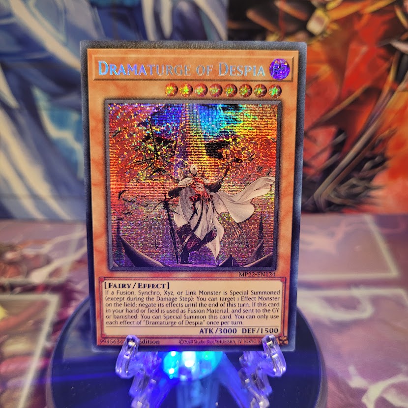 A Secret Rare "Dramaturge of Despia" card from the Yugioh 2022 Tin of the Pharaoh's Gods set.