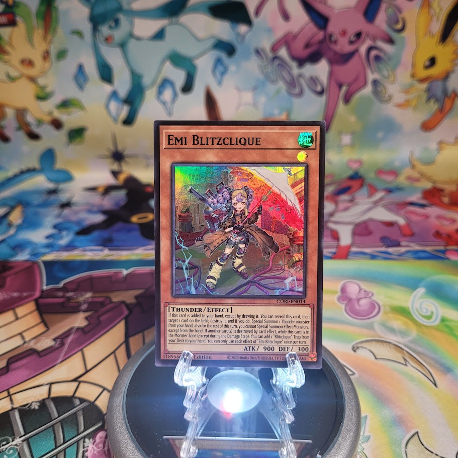 A Super Rare “Emi Blitzclique” card from the Yugioh Set: Chaos Origins (CORI).

