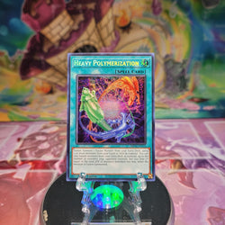 A Prismatic Secret Rare "Heavy Polymerization" card from the Yugioh Set: 25th Anniversary Tin: Dueling Mirrors (MP24).