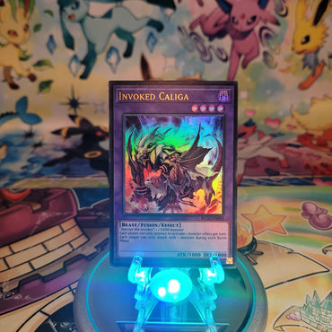 An Ultra Rare "Invoked Caliga" card from the Yugioh Set: Battles of Legend: Glorious Gallery (BLGG).