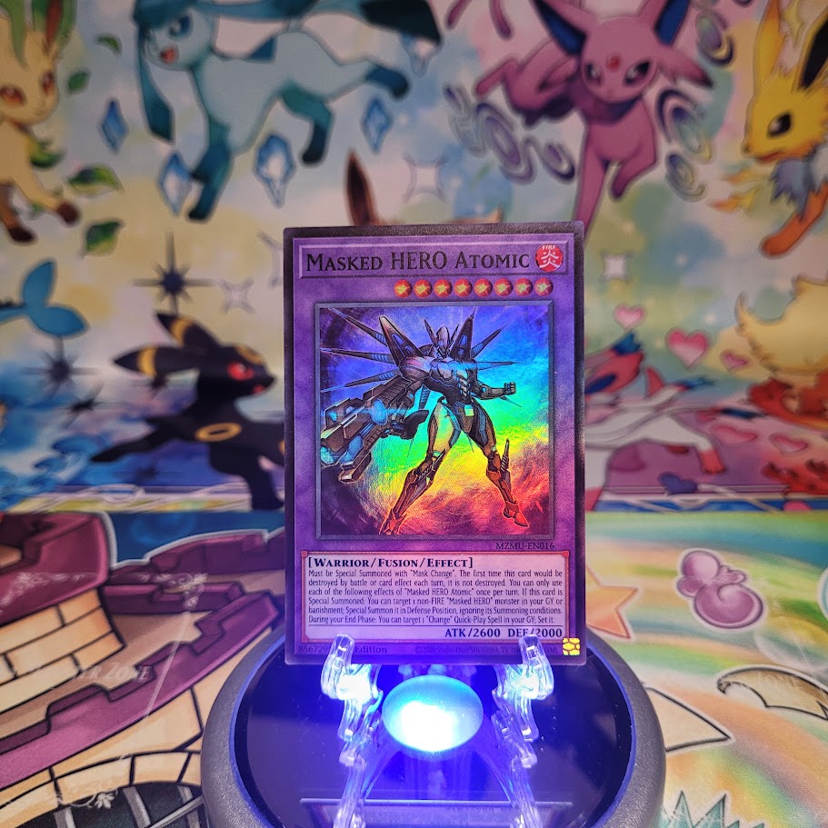 A Super Rare "Masked Hero Atomic" card from the Yugioh Set: Maze of Muertos (MZMU).