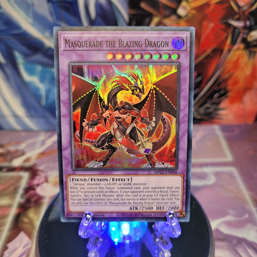 A Super Rare "Masquerade the Blazing Dragon" card from the Yugioh 2022 Tin of the Pharaoh's Gods Set (MP22).