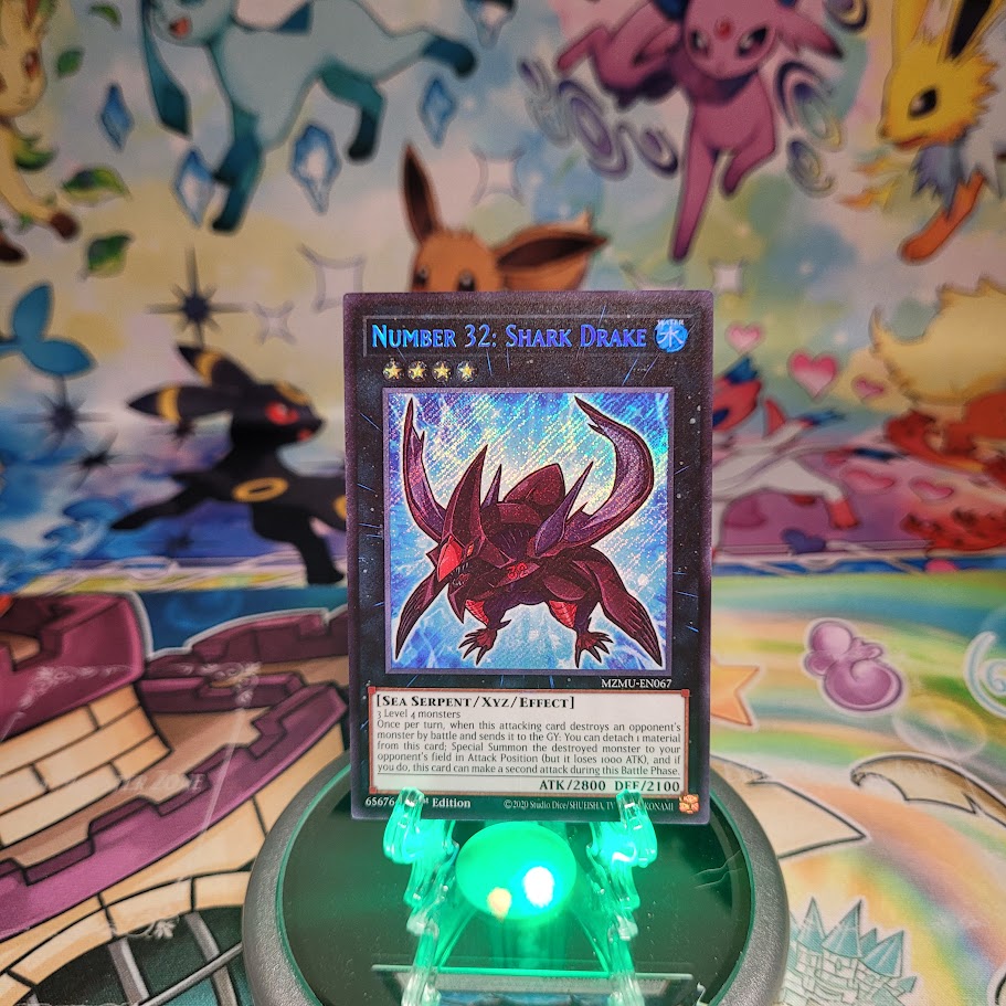 A Secret Rare "Number 32: Shark Drake" chibi art card from the Yugioh Set: Maze of Muertos (MZMU).