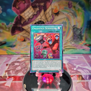 A Super Rare "Obedience Schooled" card from the Yugioh 2014 Mega-Tins Mega Pack set.