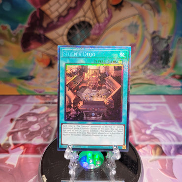 A Prismatic Collector's Rare "Shien's Dojo" card from the Yugioh Set: Quarter Century Stampede (RA04).