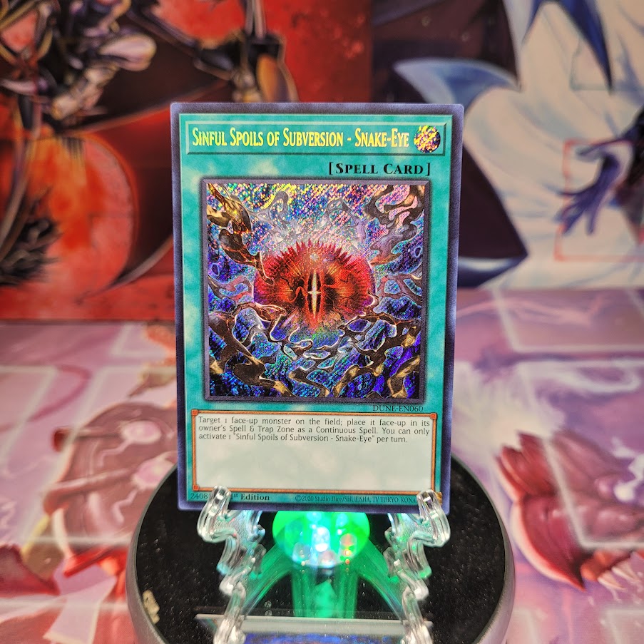 A Secret Rare "Sinful Spoils of Subversion - Snake-Eye" card from the Yugioh Set: Duelist Nexus.