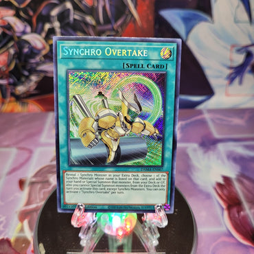  A Secret Rare "Synchro Overtake" card from the Yugioh Set: Dawn of Majesty (DAMA).
