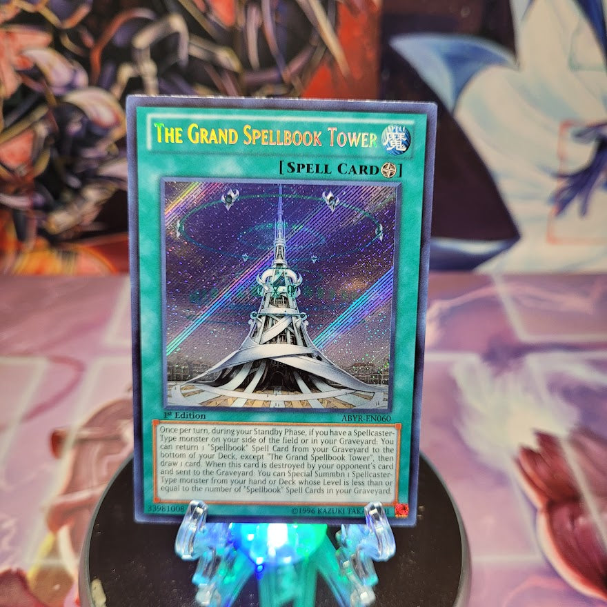 A Secret Rare "The Grand Spellbook Tower" card from the YugiohSet: Abyss Rising.