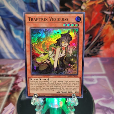 A Super Rare "Traptrix Vesiculo" card from the Yugioh 2022 Tin of the Pharaoh's Gods Set.