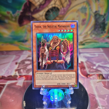 A 1st Edition Super Rare "Yasha, the Skeletal Mayakashi" card from the Yugioh Set: Hidden Summoners.